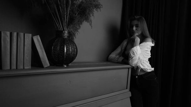 Černá a bílá fotografie mladé krásné smyslné a sexy ženy s dlouhými vlasy na sobě v bílé košili pózuje u klavíru ve studiu.   - Fotografie, Obrázek