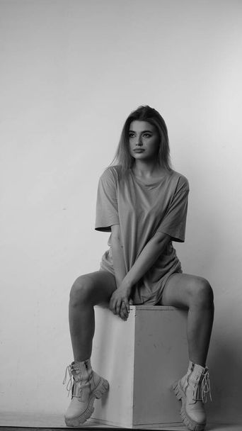 Black and white photo of young beautiful woman with long hair wearing in t-shirt in studio.   - Foto, Imagen