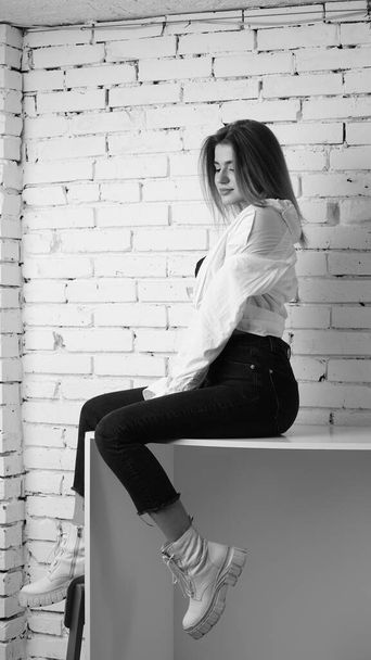 Foto en blanco y negro de una joven hermosa con el pelo largo en la camisa posando en el estudio.   - Foto, imagen