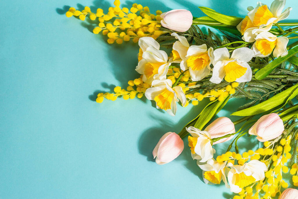 Frühlingsblumen Komposition isoliert auf blauem Hintergrund. Frohe Ostern oder Hochzeitskonzept, Valentinstag oder Muttertag, flache Lage, Draufsicht - Foto, Bild