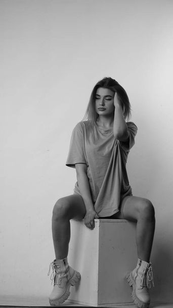 Black and white photo of young beautiful woman with long hair wearing in t-shirt in studio.   - Φωτογραφία, εικόνα