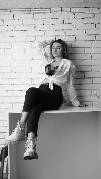 Foto en blanco y negro de una joven hermosa con el pelo largo en la camisa posando en el estudio.   - Foto, Imagen