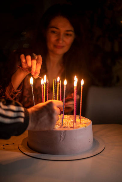 schattig meisje steekt kaarsen op een verjaardag taart, verticaal - Foto, afbeelding