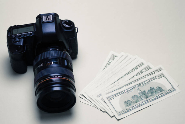 A stack of cash dollars next to a professional photo camera. The concept of earnings, the development of a photographer, the work of paparazzi, expensive photographic equipment. Copy space. - Fotoğraf, Görsel