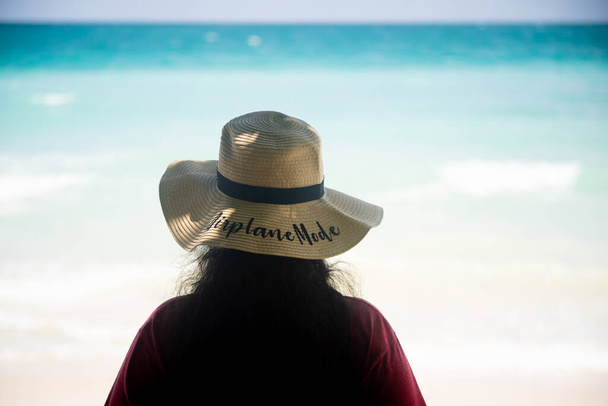 молода жінка солом'яний сонцезахисний капелюх з режимом літака, що стоїть на пляжі з синіми зеленими хвилями, що плескають узбережжя на андаманських островах у Свараджі
 - Фото, зображення