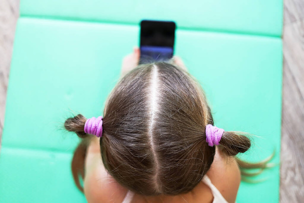 girl child with pigtails talking on the phone, getting homework on a cellular connection, during isolation and a pandemic, a convenient means of communication - 写真・画像