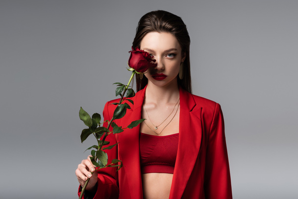 young woman in red outfit holding rose isolated on grey - Foto, Imagem
