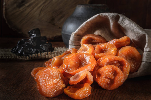 sušené meruňky v tkané tašce na tmavém dřevěném pozadí - Fotografie, Obrázek