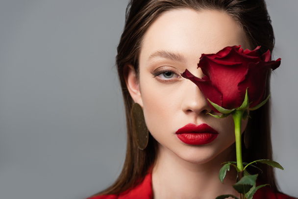 close up of young woman near red rose isolated on grey - Фото, зображення
