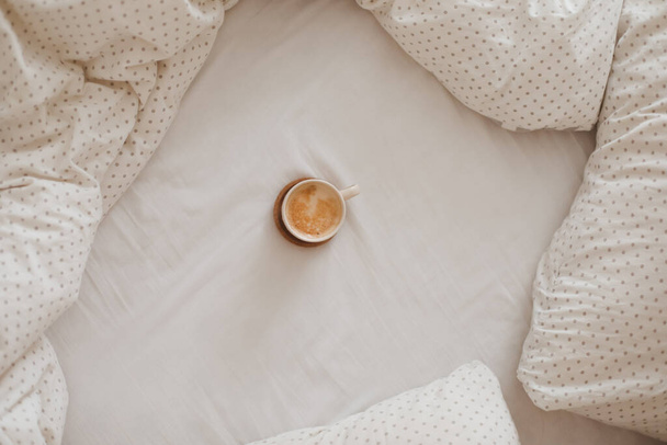 Cozy unmade bed with a coffee cup in the morning, breakfast in bed - Foto, Bild