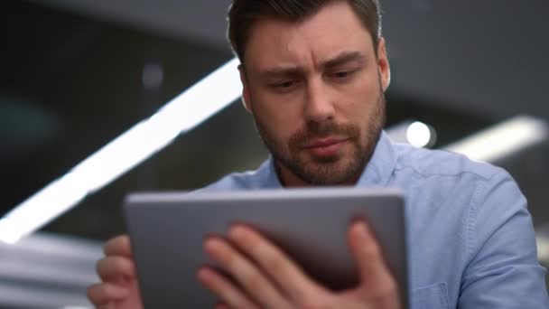 Przystojny biznesmen pracujący tablet badający oprogramowanie korporacyjne w biurze. - Materiał filmowy, wideo