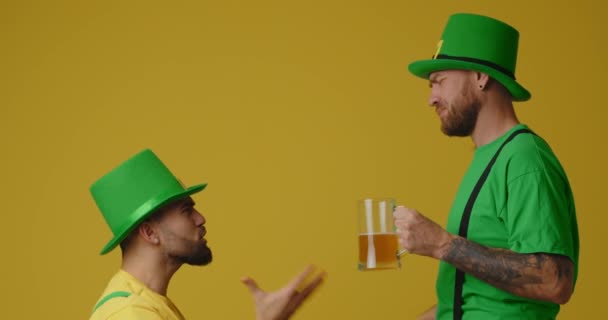 男性が主張し、ビールを飲み、黄色の背景に平和を作る。聖パトリックの日お祝い - 映像、動画