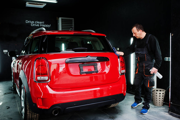 Mann wäscht rotes Auto in Garage. - Foto, Bild