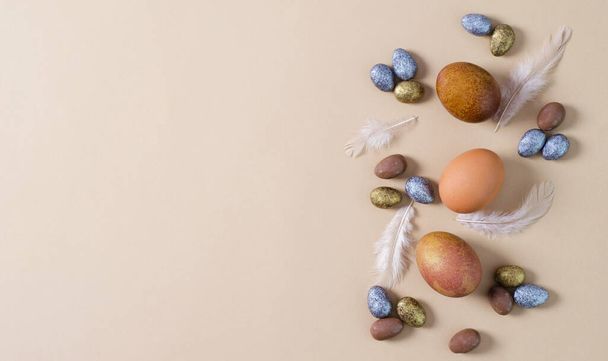 Sfondo pasquale. Uova di Pasqua dipinte e caramelle al cioccolato in smalto su sfondo marrone, spazio vuoto per il testo - Foto, immagini