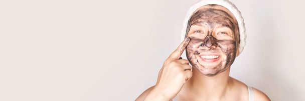 Young woman applying black face mask. Charcoal facial product. Acne and pimple - Fotografie, Obrázek