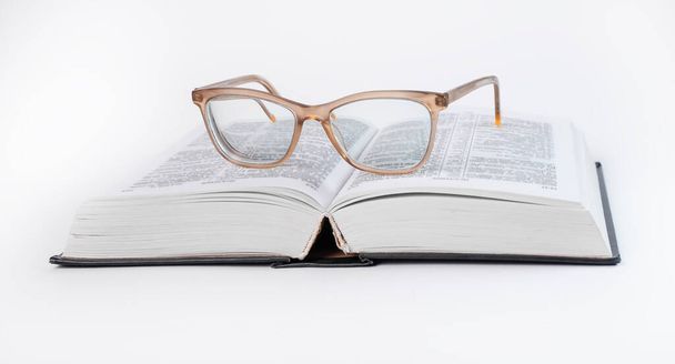 Glasses at open book. Education concept. Bible, dictionary reading.  - 写真・画像