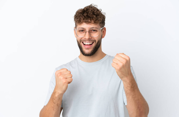Young handsome caucasian man isolated on white background With glasses and celebrating a victory - Photo, Image