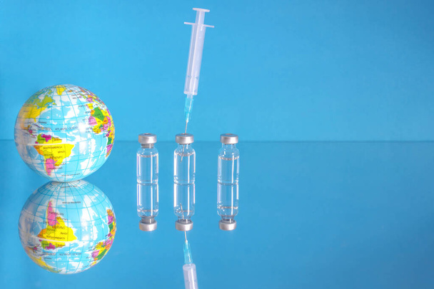 Flessen en spuit met vaccin, behandeling voor COVID-19, griep of griep, wereldwijde massale vaccinatie voor het coronavirus, globaal immunisatieconcept met derde boosterdosis - Foto, afbeelding