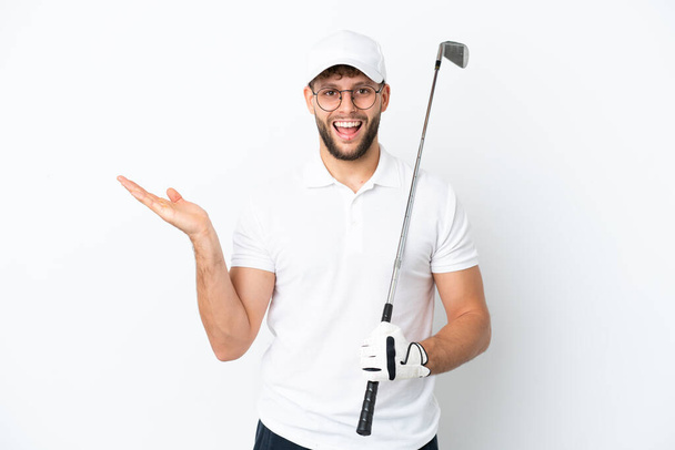 Guapo joven jugando al golf aislado sobre fondo blanco con expresión facial impactada - Foto, Imagen