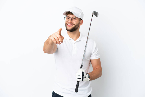 Guapo joven jugando al golf aislado sobre fondo blanco apuntando frente con expresión feliz - Foto, Imagen
