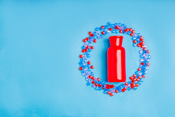 um die rote Vase ist eine Streuung blauer und roter Plastiksterne. Raum für Text lassen - Foto, Bild