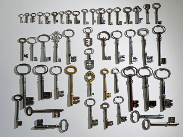 Коллекция из 48 антикварных ключей на белом фоне - Фото, изображение