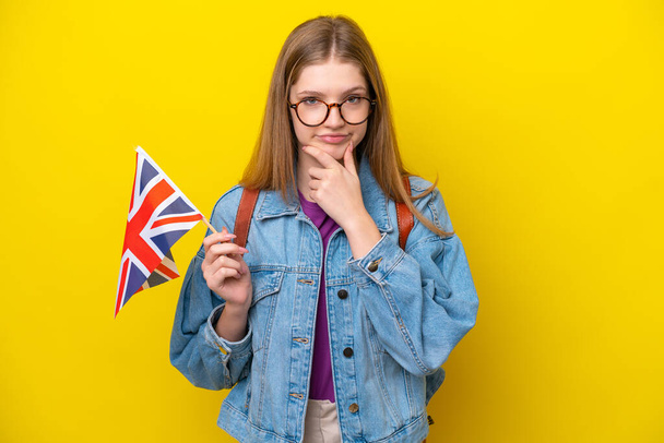 Teenager Russian girl holding an United Kingdom flag isolated on yellow background thinking - Photo, Image