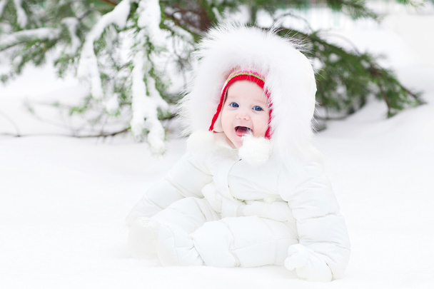 Adorable bebé riendo sentado en la nieve bajo un árbol de Navidad
 - Foto, imagen