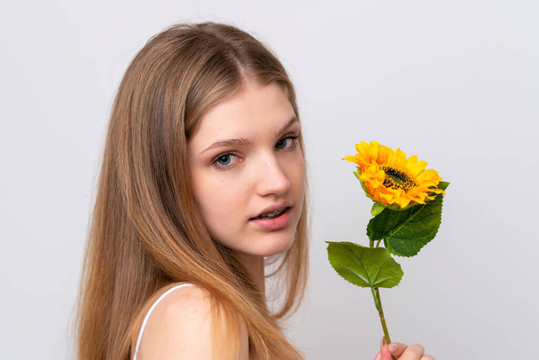 Teenager Russian girl isolated on white background holding a sunflower. Close up portrait - 写真・画像
