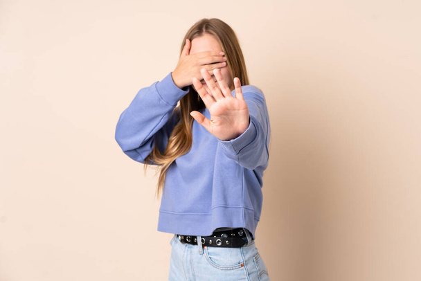 Teenager Ukrainian girl isolated on beige background making stop gesture and covering face - Zdjęcie, obraz