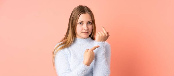 Підліткова українська дівчинка, ізольована на рожевому фоні, робить жест запізнитися. - Фото, зображення