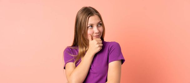 Έφηβος Ουκρανή κοπέλα απομονωμένη σε ροζ φόντο σκέφτεται μια ιδέα, ενώ ψάχνει επάνω - Φωτογραφία, εικόνα