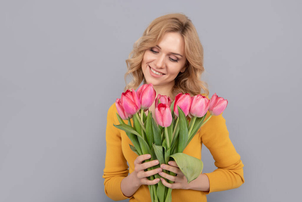 happy woman with tulips on grey background - Fotó, kép