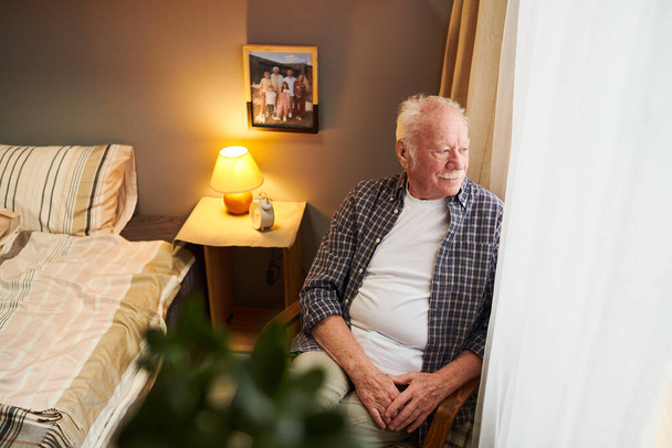 Uomo anziano sereno e rilassato seduto in poltrona dalla finestra - Foto, immagini