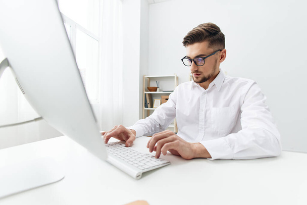 homens de negócios em uma camisa branca senta-se em um computador com um escritório de telefone - Foto, Imagem