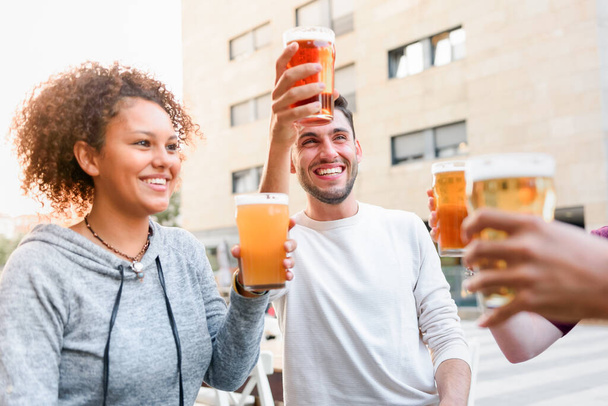 Grupo de amigos felizes batendo copos de cerveja enquanto sentados no terraço do café na cidade e passar o tempo juntos - Foto, Imagem