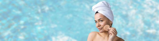 Schoonheidsportret van vrouw in witte handdoek op het hoofd brengt crème aan op het gezicht. Huidverzorging eco biologische cosmetische spa ontspannen concept. - Foto, afbeelding