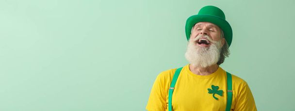 Glücklicher älterer Herr mit grünem Hut auf hellem Hintergrund mit Platz für Text. St. Patrick 's Day Feier - Foto, Bild
