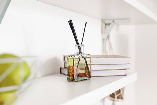 Aroma-Schilfrohrdiffusor mit Büchern im Regal im Zimmer - Foto, Bild