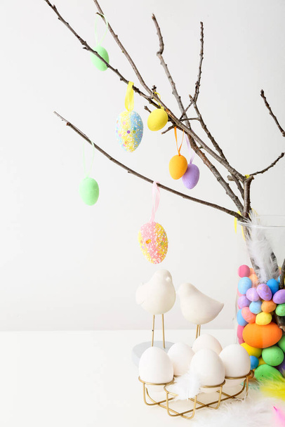 Tree branches with different Easter eggs and stylish decor on light table - Valokuva, kuva