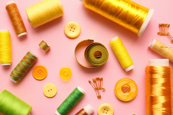 Bobinas de rosca, botones y cinta métrica sobre fondo de color - Foto, imagen
