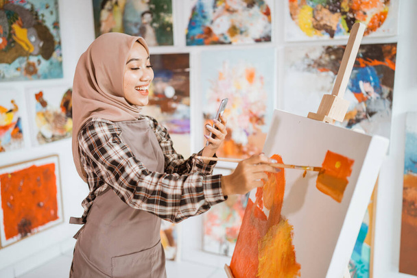 muslim female artist looking for inspiration from her mobile phone - Valokuva, kuva