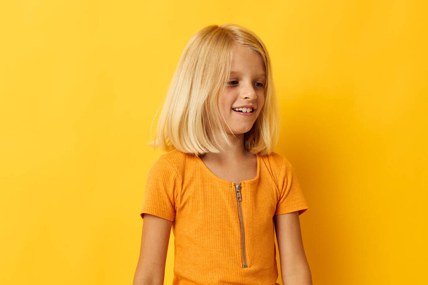 cute little girl in a yellow t-shirt smile posing studio color background unaltered - Foto, immagini