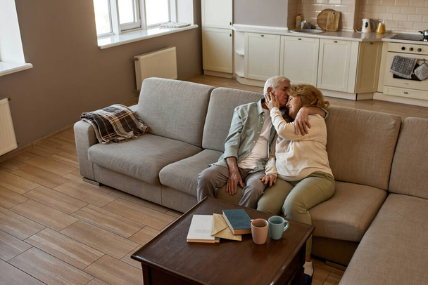 Senior european couple resting on sofa at home - Fotó, kép
