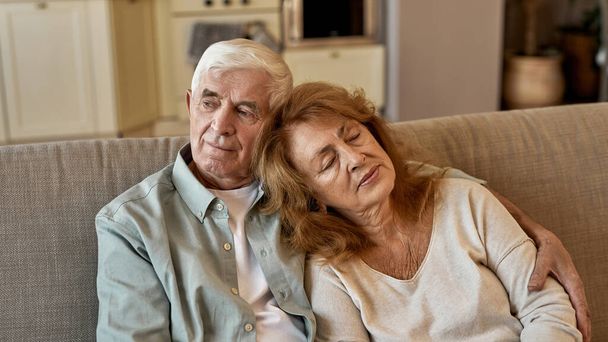 Senior european couple resting on sofa at home - Foto, imagen