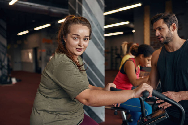 Male trainer tell to girl do exercise on orbitrek - Valokuva, kuva