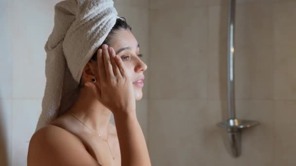Cerca de hermosa mujer semidesnuda aplicando crema facial - Metraje, vídeo