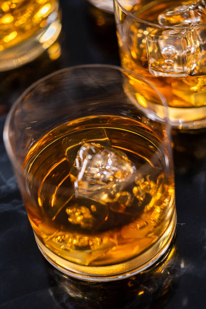 Scotch on the rocks in whiskey glass on a black marble surface. - Φωτογραφία, εικόνα