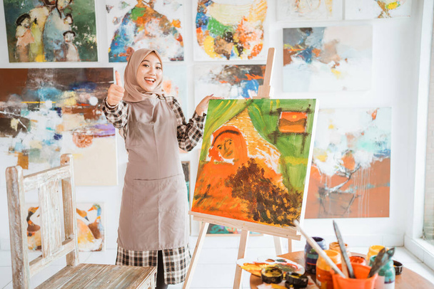 Müslüman Asyalı kadın sanatçı baş parmağını gösteriyor. - Fotoğraf, Görsel