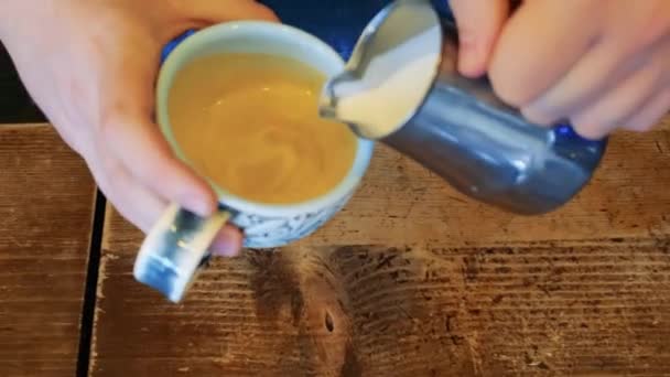 barista faz cappuccino em uma caneca de cerâmica derrama leite em café - Filmagem, Vídeo